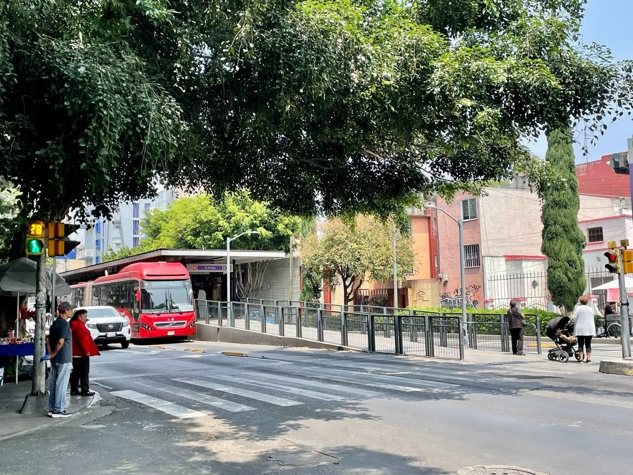 Calle arbolada con estación de Metrobús