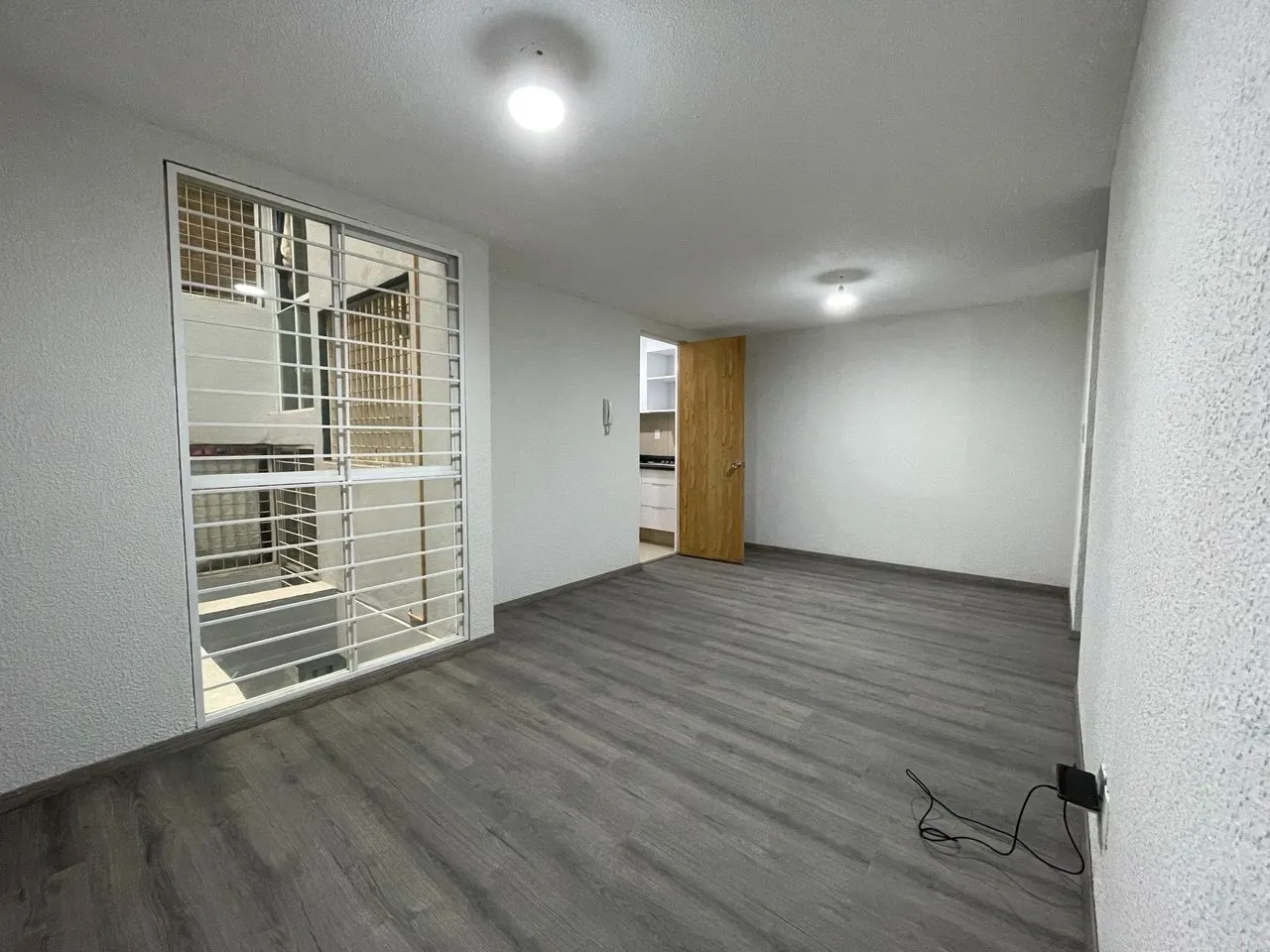 Estancia luminosa con piso laminado y ventana amplia